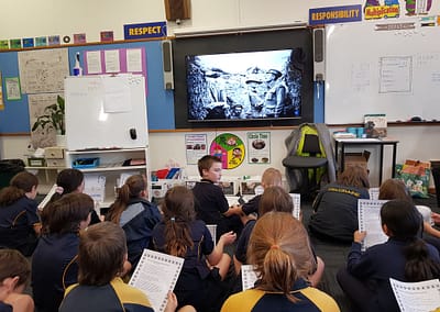 Students in classroom watching a video on the screen about the ANZACs