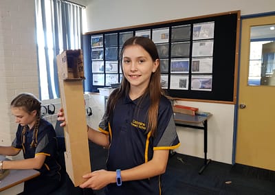 school girl holding a periscope made from cardboard